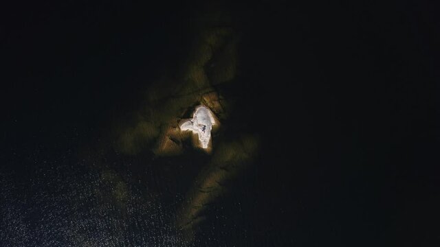 A girl sunbathes on a stone island in the middle of a lake in Karelia, Russia.