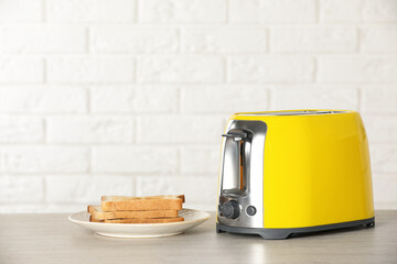 Electric toaster with bread slices on wooden table. Space for text