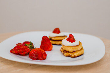 Delicious homemade pancakes with strawberries on plate on a light background
