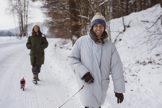 Happy women walk dogs in white snow road smiling in winter in czechia