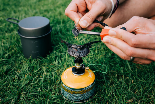 man lighting a portable stove on a campsite