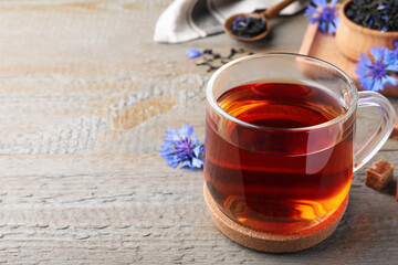 Glass cup of tea and cornflowers on wooden table, closeup. Space for text