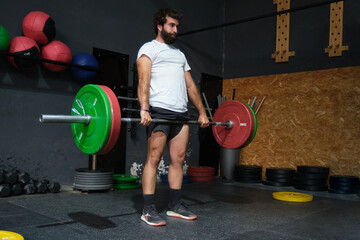 Young bearded man doing deadlift exercise in a crossfit gym.