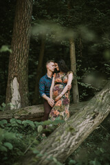 Pregnancy, parenthood concept. Happy pregnant couple, standing in beautiful summer forest, hugging and smiling each other