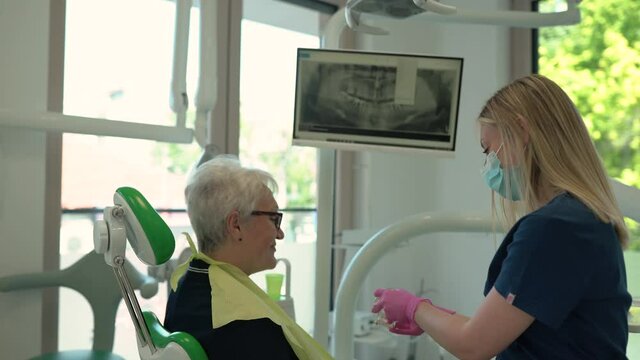 Dentist explaining using a dental model and tools.