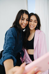 young, cheerful armenian women taking selfie on cellphone, blurred foreground