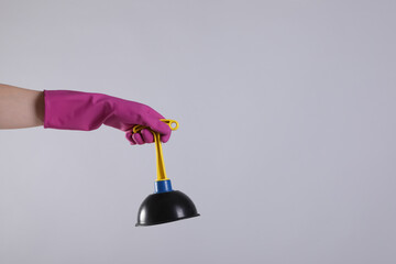 Woman holding plunger on light grey background, closeup. Space for text
