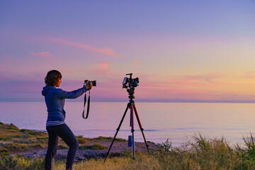 Woman with camera take travel photo at sunset