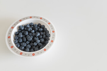 Blueberry on the plate on the white table background. Minimalistic food organic natural wallpaper