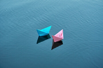 Two boats of blue and pink color, swim on the river. Summer day, rest on the pond