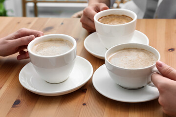 Women with cups of coffee at table in cafe, closeup