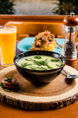 Delicious Soup Bakery Green Spinach Vegetables Carrot Sausage Cream in a black bowl on a wooden table