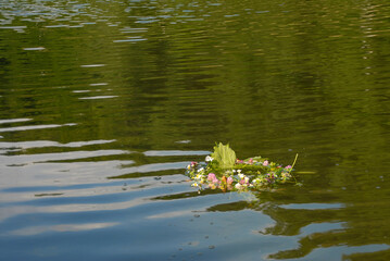 A wreath of wildflowers is floating on the water. Ukrainian holiday of Ivan Kupala in summer.