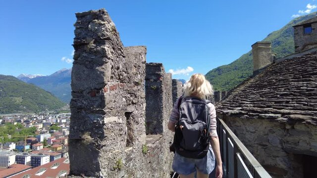 Woman walking on the walls of Swiss castle of Bellinzona, historic city in Switzerland. Aerial view lookout from Montebello castle. Bellinzona cityscape, capital city of Ticino canton in Switzerland.