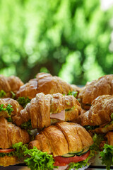 Sandwiches with croissants, ham, tomato and lettuce. Lots of delicious quick healthy food. Snack at the event.