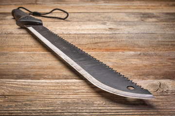 bush clearing machete with carbon steel blade and saw against rustic wooden deck