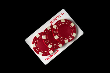 Joker card and red chips in the black background. Winning combination at a poker club or casino. Free advertising space