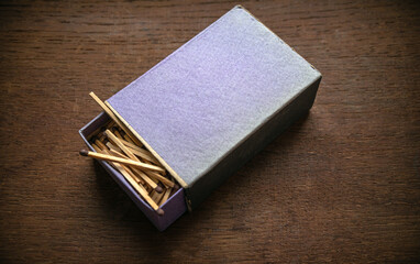 A cardboard box with matches is lying on a wooden table in a retro style
