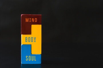 Three puzzles of different colors. The inscription on the puzzles soul, body,mind. Dark background. Copy space.