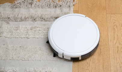 Obraz na płótnie Canvas Cleaning robot vacuum in action on the hardwood parquet and the carpet; home and domestic life. RF photo, no logos