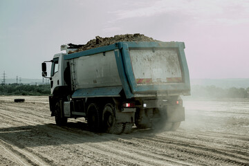 Dump truck unloads clay soil for the construction of a new highway. Clay for laying the foundation of a new road. © Oksana