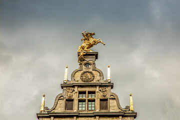 Fototapeta na wymiar roofs of ancient buildings with gilded figures against a gray sky in antwerp on the central square