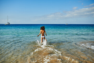 Happy woman running on the beach during summer vacation - Focus on female back