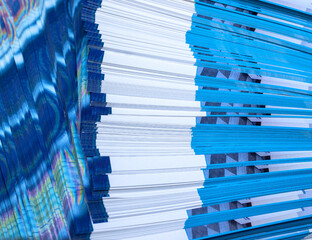 Close up edge of color, blue and white, leaflets, brochures stacked on top of each other, with...