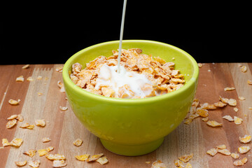 Green bowl with cereal and milk on a wooden table