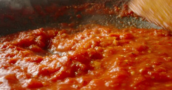 Tomato sauce boiling in a pan, being stirred with a spoon. Hot tomato sauce cooked for pizza or pasta. Italian cuisine, food and drink 4k footage