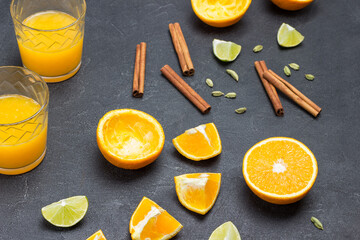 Chopped oranges and cinnamon sticks on table. Two glasses of orange juice