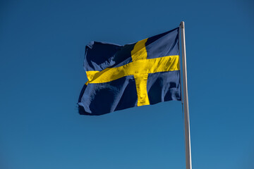 The Swedish flag blowing in the wind with a blue sky