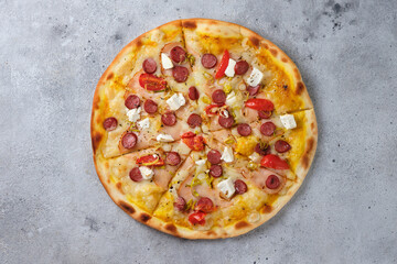 Pizza with tomatoes, ham, onions, feta cheese, mozzarella cheese, spicy sausages, spices and mustard sauce. Flat lay. On a light background