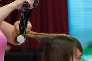 Beautiful teen girl at the hairdresser blow drying her hair after cutting it