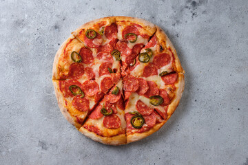Pepperoni pizza with jalapeno peppers. A closeup of a pizza. Flat lay. On a light background