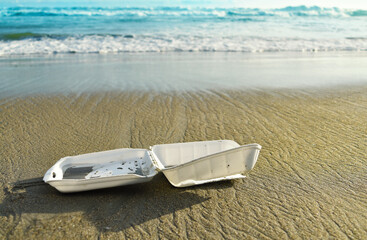 Styrofoam disposable food box on the beach, pollution, waste on sand beach