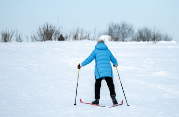 A woman in a blue jacket skiing up a snowy slope.