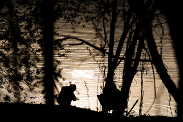 Silhouettes of children sitting by the water with ripples, abstract view