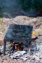 Empty stone grill plate heated by wood and smoke going to the atmosphere. Bbq in the nature