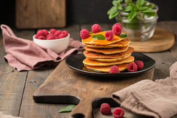 Flavored pancakes with honey and fresh raspberries for breakfast. Great breakfast dessert, garnished with fresh mint leaves.