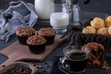 a cup of coffee, chocolate muffins, cheese breads and milk