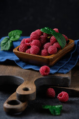 Fresh raspberries in a wooden plate on kitchen boards.