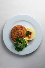 Menu for the restaurant: Cordon bleu with potatoes, lettuce, cherry tomato and lemon.