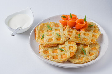 Hearty potato pancakes with red fish, garnished with fresh green onions. Dish on a white plate.