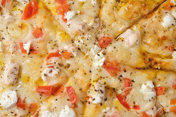 Pizza with tomatoes, chicken, onions, feta cheese, mozzarella cheese and spices. A closeup of a pizza.