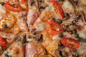 Pizza with tomatoes, ham, capers, mushrooms, mozzarella cheese, spices, sesame seeds and tomato sauce. A closeup of a pizza.