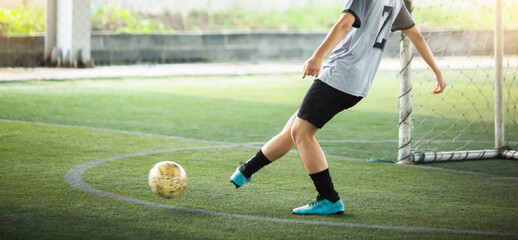Soccer player running to kicking with blurry ball on green artificial turf.  Football player in...