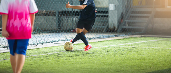 Soccer player shoot the football through the back of the leg.