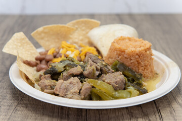 Delicious chunks of chile verde pork meat smothered in green sauce and served with rice and beans