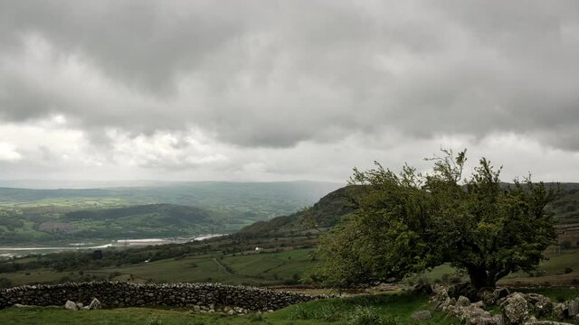 Time lapse of a storm rolling in over a Snowdonia valley in Wales, UK. Low rain clouds develop and precipitate as they roll down the valley with the sun peeking through where it can. A traditional dry